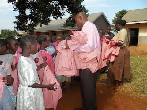 school children at St. Paul Bulega primary school receive their new school uniforms